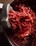 Process of preparing forcemeat by means of a meat grinder. Fresh red mincing close-up on black background with copy