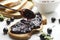 Process of spreading of sweet delicious jam on the slice of bread.Closeup of spoon, blackcurrant jam, berries, bread on the white