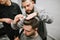 The process of styling a stylish men`s hairstyle in a barbershop. Barber combs the client`s hair with a comb and hands. Focus on