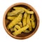 Processed turmeric rhizomes in a wooden bowl over white