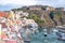 Procida, Italy. Panoramic view of Marina Corricella with pastel coloured houses, and Terra Murata at the top of the cliff.