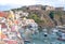 Procida, Italy. Panoramic view of Marina Corricella with pastel coloured houses, and Terra Murata at the top of the cliff.