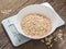 Product weighing concept. Oatmeal in a white bowl on the kitchen scales on wooden background