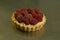 The production process for sweet pastries with fruits. The tartlet with raspberries and cream is ready