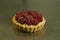 The production process for sweet pastries with fruits. The tartlet with raspberries and cream is ready