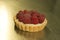 The production process for sweet pastries with fruits. The tartlet with raspberries and cream is ready