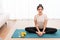 Productive activity concept a girl with a bun sitting on the rectangular green mat stretching her both legs parallel to the floor