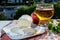 Products of Normandy, cow neufchatel lait cru cheese and glass of apple cider drink with houses of Etretat village on background,