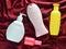 Products for the shower and for beauty: shampoo, shower gel, liquid soap, perfume on a red silky background.