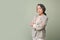 Professional 60s senior Asian female CEO serious, arms crossed, isolated green background