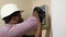 Professional african american electrician in a hard hat and plaid shirt installing an electrical box in a wall