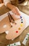 Professional artist squeezing oil paint from tubes on wooden pal