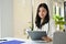 Professional Asian businesswoman reading and reviewing business report, working at her desk