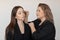 Professional attractive make-up artist brushing eyebrow with mascara brush of young beautiful woman with closed eyes.