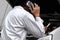 Professional automotive mechanic in uniform talking on phone and examining engine under hood of car at the repair garage.