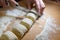 professional baker with knife cuts the raw sausage dough into even small pieces