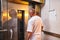 Professional baker in uniform stands near industrial oven in a bakery for making bread