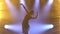 Professional ballerina dancing ballet in spotlights and smoke on stage. Silhouette of a beautiful slim figure.