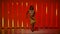 A professional ballerina is dancing in the studio against the background of bright red orange neon tubes. A beautiful