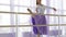 Professional ballerina is puts her leg on the barre stand.