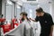 Professional barber with a hair clipper in a back hair cuts an adult client`s hair with a beard. Focused male hairstylist creates