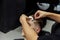 Professional barber with open cutthroat razor shaves hair on man`s temples. Attractive male is getting a modern haircut