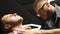 Professional barber shaves customer beard with straight razor. Beard cut with old-fashioned blade at barbershop