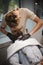 A professional barber shaving a handsome man who sitting in a barber chair on a blurred light background.