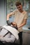 A professional barber shaving a handsome man who sitting in a barber chair on a blurred light background.