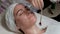 Professional beautician applying cosmetic mask on female neck at beauty salon. The procedure for applying a transparent gel with a