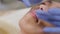 Professional beautician lubricates the lips of a woman after the procedure.