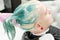 Professional beauty salon: hairstylist hands washing green hair of young woman with shampoo in sink