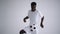 A professional black football player in a white uniform on a white background juggles a ball in slow motion. African