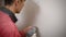 A professional builder makes symmetrical holes in a plasterboard wall using an electric drill, a man screws the wall