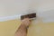 Professional builder smooths wall with spatula putty put on leveled surface of wall