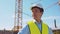 Professional builder standing in front of construction site. Foreman in hardhat helmet and vest. Office building and