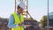 Professional builder standing with tablet computer in front of construction site. Foreman in helmet and vest. Office