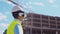 Professional builder in VR helmet standing in front of construction site and using virtual and augmented reality