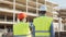 Professional builders standing in front of construction site. Office building and crane background.