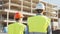 Professional builders standing in front of construction site. Office building and crane background.