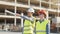 Professional builders standing in front of construction site. Office building and crane background.