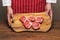 Professional butcher in classic red and white apron holding cutting board with fresh uncooked lamb loin chops. Meat industry