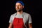 Professional butcher fishmonger in grey t shirt and classic red and white stripe apron and blue baseball hat.