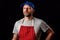 Professional butcher fishmonger in grey t shirt and classic red and white stripe apron and blue baseball hat. Man with beard in hi