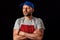 Professional butcher fishmonger in grey t shirt and classic red and white stripe apron and blue baseball hat. Man with beard in hi