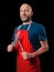 Professional butcher fishmonger wearing blue t shirt and classic red and white apron. Caucasian hipster male in his 40s; black and