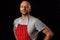 Professional butcher fishmonger wearing grey t shirt and classic red and white apron. Caucasian male in his 40s; black and grey