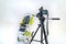 Professional camera is focused on a green pram that stands on a white background of room