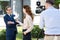 professional cameraman and female journalist interviewing cheerful businessman