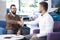 Professional car dealer shaking hands with buyer after transaction in the showroom